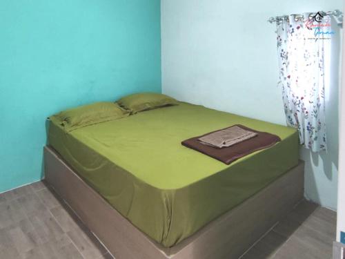 a green bed in a room with a curtain at Rumah Teman Hostel in Semarang