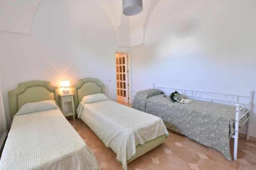 een slaapkamer met 2 bedden en een lamp erin bij Villa Giovanna Trullo in Ostuni