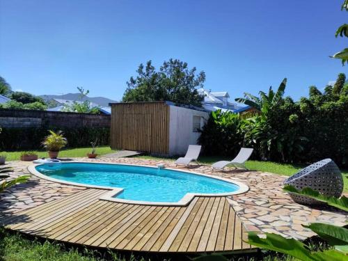 ein Pool in einem Garten mit Stühlen um ihn herum in der Unterkunft Charmante villa créole climatisée, jardin tropical et piscine privés in Lamentin