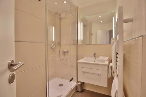 uma casa de banho com um chuveiro, um lavatório e um espelho. em Residenz Ostseestrand Residenz Ostseestrand Appartement 17 em Scharbeutz