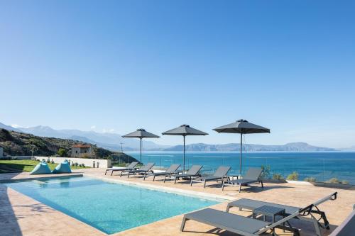 een zwembad met stoelen en parasols naast het water bij Pietra Di Mare in Petres
