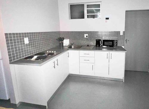 una pequeña cocina con armarios blancos y fregadero en `Luxury Cosy City Apartment, en Johannesburgo