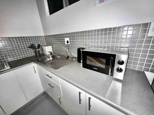 cocina con fregadero y microondas en `Luxury Cosy City Apartment, en Johannesburgo