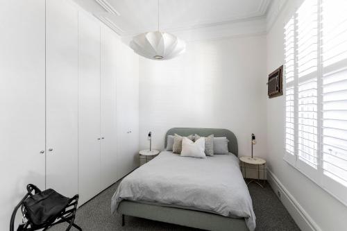 1 dormitorio con paredes blancas y 1 cama con 2 mesas en Circa 1890, en Melbourne