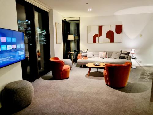 a living room with orange chairs and a couch at Luxe Waterfront Melbourne in Melbourne