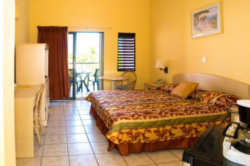 a hotel room with a bed and a balcony at Allamanda Beach Resort in Grand Anse