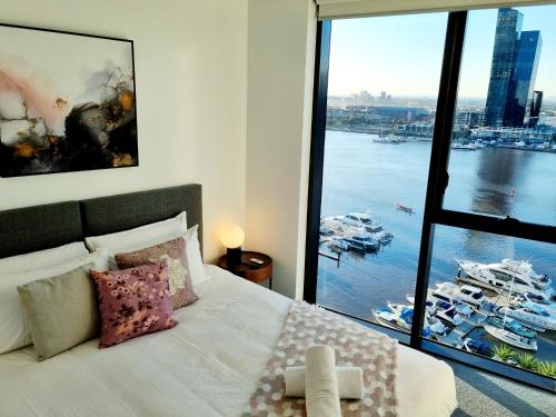 a bedroom with a large window with boats in the water at Luxe Waterfront Melbourne in Melbourne