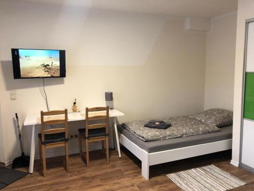um quarto com uma secretária, uma cama, uma mesa e cadeiras em GottwaldHaus-Freiberg-Apartment / A em Freiberg