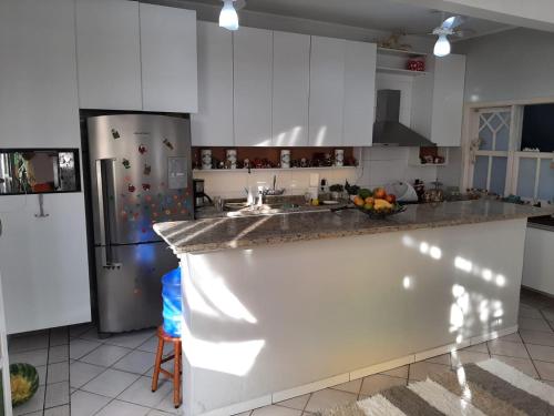 a kitchen with white cabinets and a stainless steel refrigerator at Tartaruga Marinha Guest House in Ubatuba