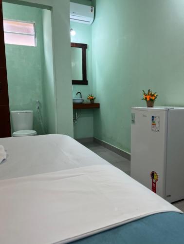 Zimmer mit einem weißen Bett und einem Kühlschrank. in der Unterkunft Pousada Certa Express in Chapada dos Guimarães