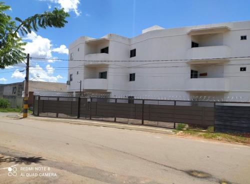 a white building with a fence next to a street at Moria in Goiânia