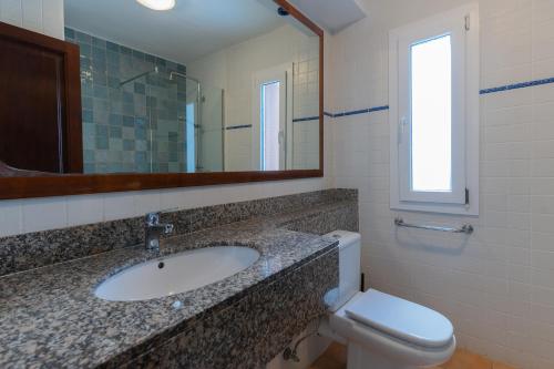 un bagno con lavandino, WC e specchio di Apartamento Ferrera Park 305 a Cala Ferrera