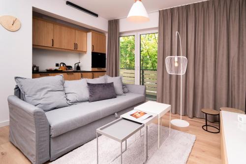 a living room with a grey couch and a kitchen at M2 Resort Wellness & Spa in Ostrowo