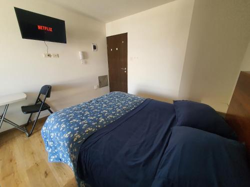 een slaapkamer met een bed met een blauw dekbed en een bureau bij Céntrico monoambiente en el prado in Cochabamba