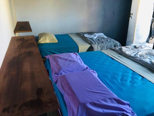 a bedroom with two beds and a wooden table at Pensão Repouso Alegre Turismo e Aventura in Portela