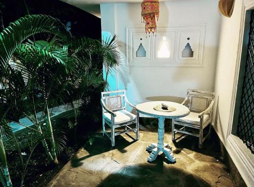 a room with a table and two chairs and a plant at WHITE Nyumba Malindi in Malindi