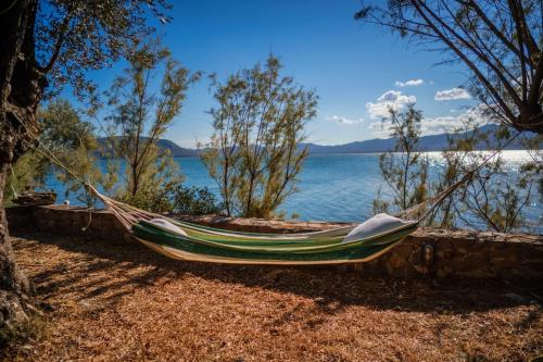 a hammock sitting next to a body of water at Seafront Traditional Stone House in Sunset Olive Grove - B in Alyfantá