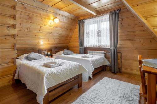 a bedroom with two beds in a log cabin at Villa Kucówka in Brzegi