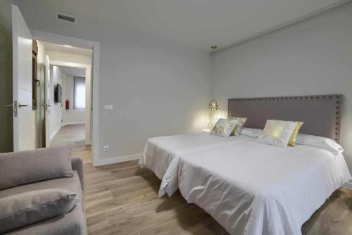 una camera bianca con un grande letto e un divano di Apartamento rural Las Cañas Esencia de Bardenas a Villafranca