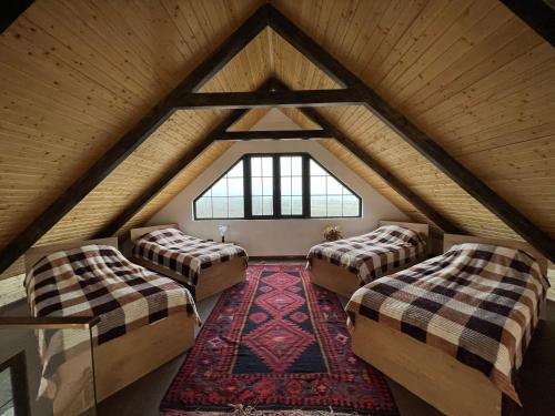 a attic room with two beds and a rug at Qafqaz Suite Wood Stack in Gabala