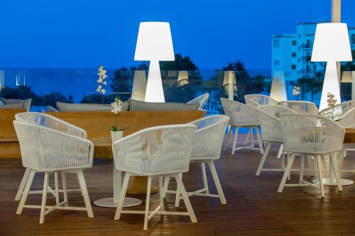 a row of white chairs and tables on a deck at Odessa Beach Hotel in Protaras
