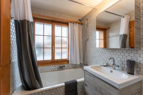 a bathroom with a tub and a sink and a mirror at Cozy Place in Gstaad center in Gstaad