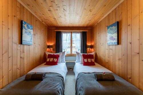 2 Betten in einem Zimmer mit Holzwänden in der Unterkunft Cozy Place in Gstaad center in Gstaad
