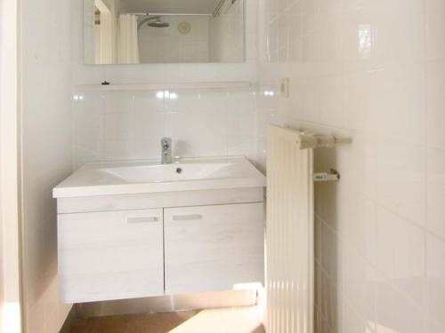 een witte badkamer met een wastafel en een spiegel bij Elli in Cadzand-Bad