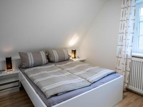 a white bed in a room with two lamps at Ferienwohnung Wrixumer Marsch in Wrixum