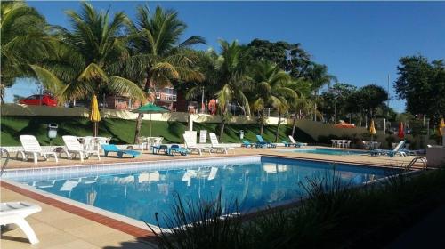 a large swimming pool with chairs and palm trees at Estada inesquecível 01 Guarapari in Guarapari
