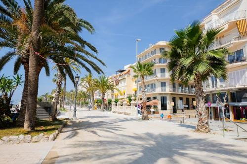 a street with palm trees and a building at Hotel Subur in Sitges