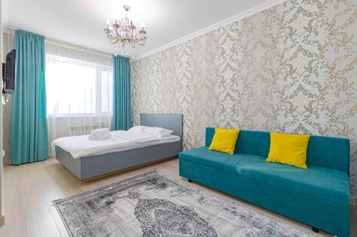 um quarto com uma cama e um sofá azul em ЖК 7Я em Astana
