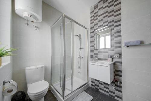uma casa de banho branca com um chuveiro e um WC. em CityVista - Gzira Apartments and Penthouse by ShortletsMalta em Il-Gżira