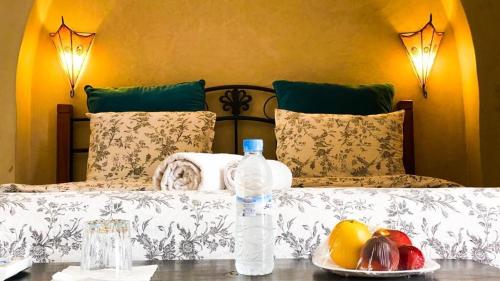 a bed with a bottle of water and fruit on a table at Riad BB Marrakech in Marrakesh