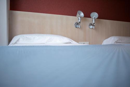 a bed with two white pillows and two lights on it at El Globo in Valencia