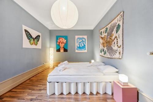 Un dormitorio con una cama blanca en una habitación con pinturas en Villa Bellevue Rüschlikon en Rüschlikon