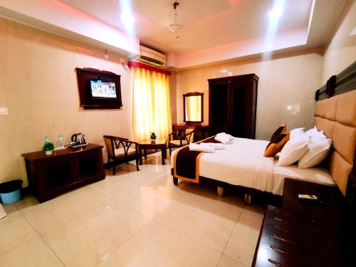 a hotel room with a bed and a television at HOTEL YUVRAJ SIGNATURE in Mysore