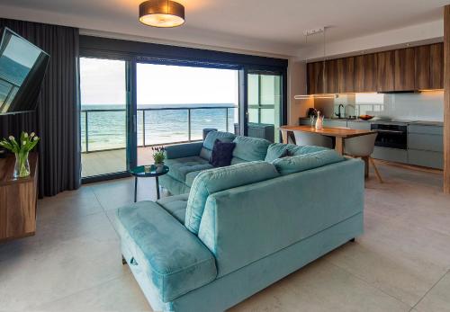 salon z niebieską kanapą i kuchnią w obiekcie Floryda Gardenia Seaside w Dziwnowie