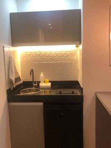 uma cozinha com lavatório e um balcão com luz em Flat no Transamerica Hotel em Campos dos Goytacazes