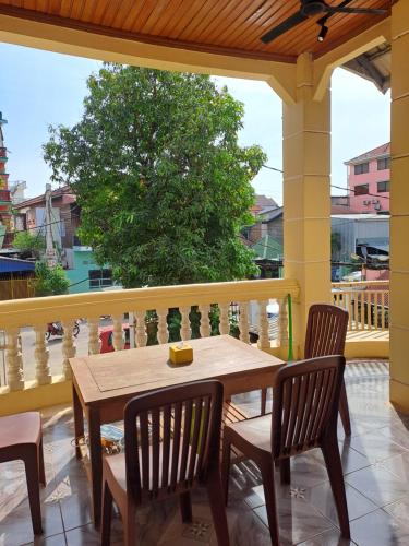 a wooden table and chairs on a balcony with a tree at Makers Guesthouse in Siem Reap