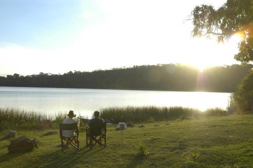 two people sitting in chairs in front of a lake at Arusha Serena Hotel in Nkoanrua