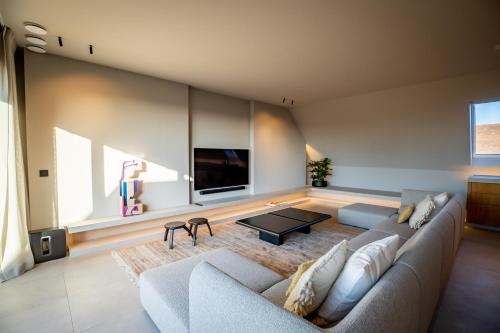 a living room with a couch and a tv at The Penthouse Nami, Branding, Ultra Luxurious Japanese Design Sea View in Cadzand