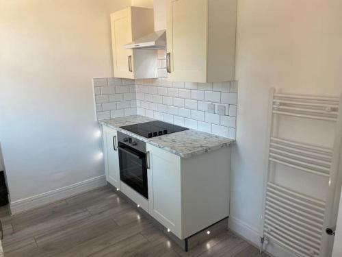 a kitchen with white cabinets and a stove at Coastal Retreat-NEW DAY PROPERTIES-next to beach in South Shields