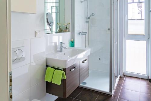 a white bathroom with a sink and a shower at Villa Lena mit Fahrstuhl und Bäcker im Haus, direkt an der Flaniermeile in Ostseebad Sellin