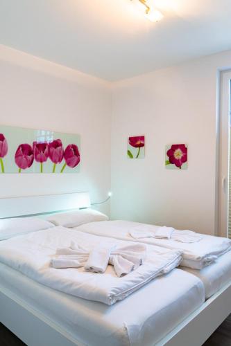 a white bed in a room with pink flowers on the wall at Villa Lena mit Fahrstuhl und Bäcker im Haus, direkt an der Flaniermeile in Ostseebad Sellin