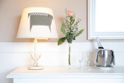 a table with a lamp and a vase of flowers on it at Hotel Baia Di Nora in Pula