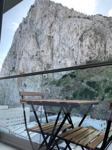 a table and chair on a balcony with a mountain at CP High floor luxury studio in Gibraltar