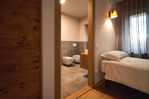a bedroom with a bed and a bathroom with a toilet at Hotel Ristorante Pennar in Asiago