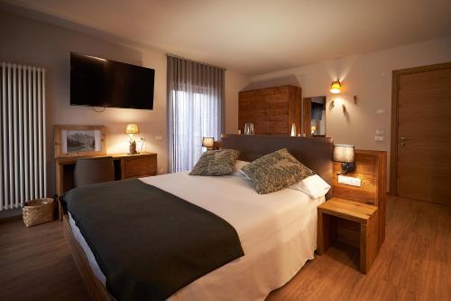 a bedroom with a large bed and a flat screen tv at Hotel Ristorante Pennar in Asiago