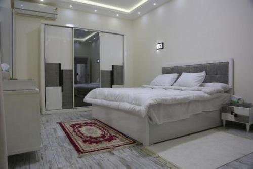 ein weißes Schlafzimmer mit einem Bett und einem Spiegel in der Unterkunft فيلا الياسمين in ‘Ezbet `Abd el-Ḥamîd
